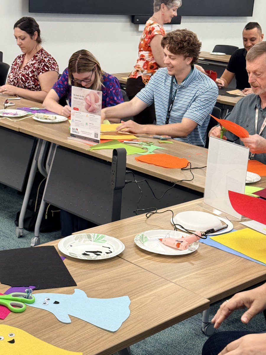 Booz Allen Hamilton volunteers working together at a table to make colorful felt costumes for NICU babies.