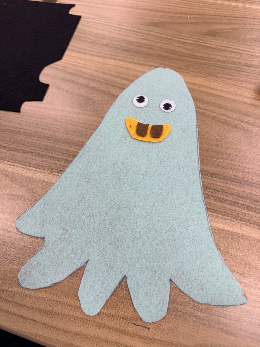 Close-up of a pale green handmade felt ghost costume with large eyes and a playful smile.