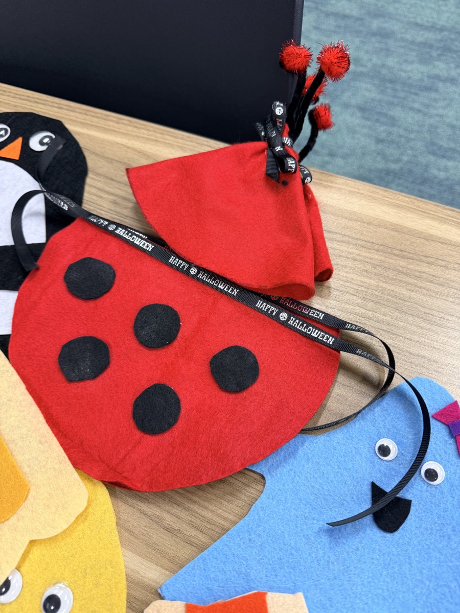 Close-up of handmade red ladybug and blue penguin costume pieces with Halloween ribbons.
