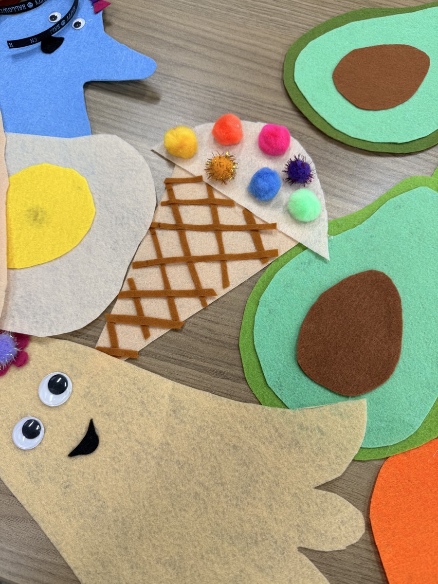 Close-up of handmade felt avocado, ice cream, ghost, and other colorful Halloween costume pieces.