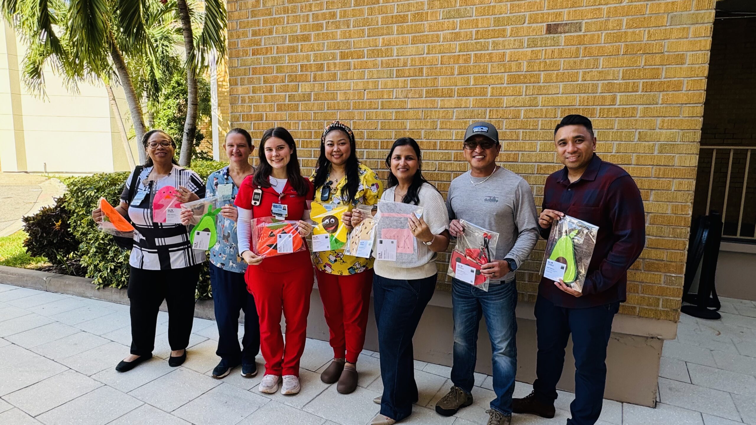 People holding packaged handmade costumes during the 2026 Tampa General Hospital NICU donation.
